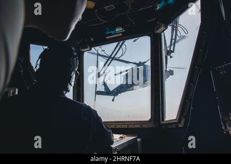 220222-N-GF955-1005 KARIBISCHES MEER - (FEB 21, 2022) -- die Mate 1.-Klasse von Boatswain Emmanuel Dixon, die dem Freedom-Variant Littoral Combat Ship USS Billings (LCS 15) zugewiesen wurde, beobachtet vom Flugkontrollturm aus einen MH-60s Sea Hawk Hubschrauber, der dem „Shadow Det“ des Helicopter Sea Combat Squadron (HSC) 28, Ablösung 7, Hebt vom Flugdeck ab, 21. Februar 2022. Billings wird in den Einsatzbereich der US-Flotte für 4. eingesetzt, um die Mission der Joint InterAgency Task Force South zu unterstützen, die Missionen zur Bekämpfung des illegalen Drogenhandels in der Karibik und im östlichen Pazifik umfasst. (USA Stockfoto