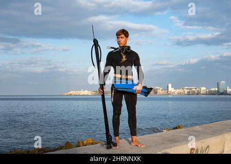 Gut aussehende junge Fischer posiert für die Kamera, bevor sie im Ozean vor der Malacon-Meeresmauer in Havanna, Kuba, fischen gehen. Stockfoto