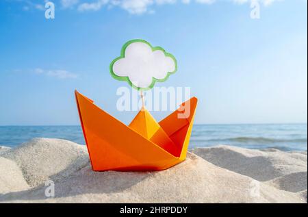 Orange Papier Boot auf Sandy Seashore Nahaufnahme kleines Boot aus Papier auf dem Hintergrund Stockfoto