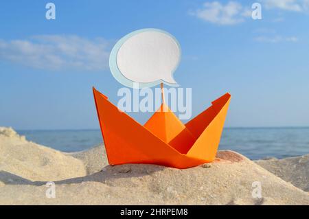 Orange Papier Boot auf Sandy Seashore Nahaufnahme kleines Boot aus Papier auf dem Hintergrund Stockfoto