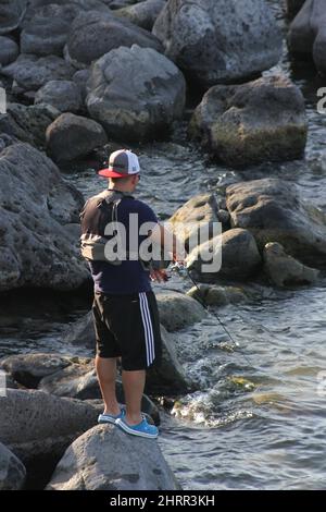 Ein Fischer balanciert auf einem Felsen, während er aus dem See von Galilee in Israel fischt. Stockfoto