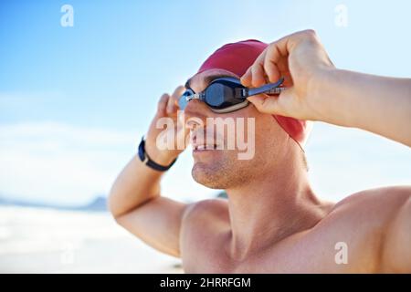 Schutzbrille an. Nahaufnahme eines Mannes, der eine Schwimmbrille trägt und auf das Meer blickt. Stockfoto
