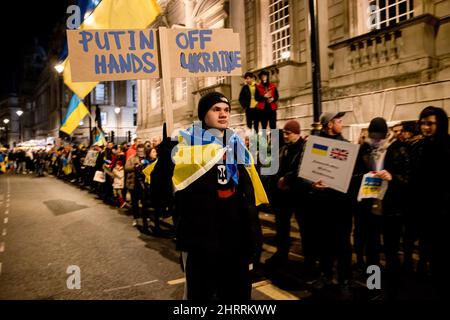 London, Großbritannien. 25.. Februar 2022. Ein Protestler hält ein Plakat, während er während der Demonstration durch die Whitehall geht.Mehr als Tausende Ukrainer und ihre Anhänger versammelten sich am zweiten Tag vor der Downing Street, seit Putin die Invasion der Ukraine erklärt hat. Sie forderten die Welt auf, rasch zu handeln, um Russland zu sanktionieren, einschließlich Russland von SWIFT abzuschneiden. Kredit: SOPA Images Limited/Alamy Live Nachrichten Stockfoto