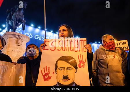 Madrid, Spanien. 26.. Februar 2022. Ein Protestler hält ein Plakat mit dem Gesicht des russischen Präsidenten Wladimir Putin und den Worten "genug" während einer Demonstration gegen den Krieg zwischen Russland und der Ukraine und die Rolle der NATO auf dem Puerta del Sol Platz in Madrid. Kredit: SOPA Images Limited/Alamy Live Nachrichten Stockfoto