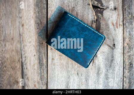 Leder marineblau mit weißem cremefarbenem Portemonnaie, handgefertigt auf Holzhintergrund, echtes pflanzlich gegerbtes Leder Stockfoto