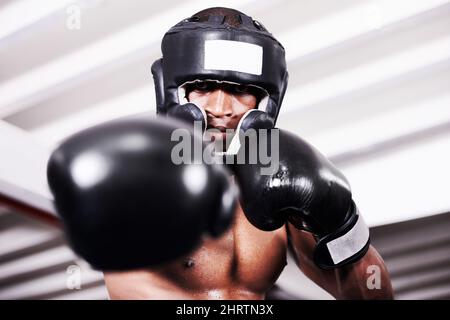 Ich nehme Euch einen. Ein afroamerikanischer Boxer, der Schutzkleidung trägt und im Ring steht. Stockfoto