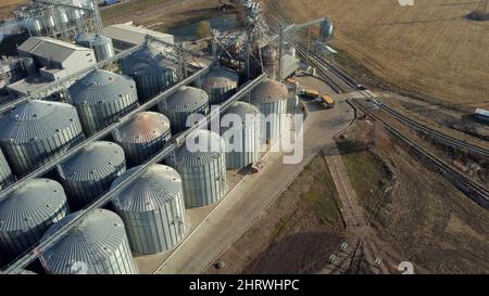 Lastwagen voller Getreide fährt an sonnigen Tagen in der Nähe großer Metallsilos des Getreideaufzugs. Stockfoto