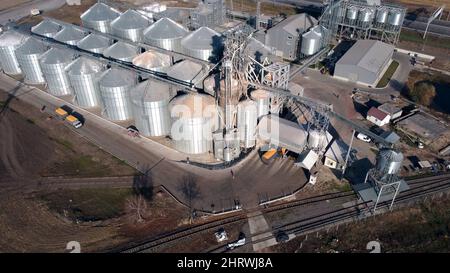 Lastwagen voller Getreide fährt an sonnigen Tagen in der Nähe großer Metallsilos des Getreideaufzugs. Stockfoto