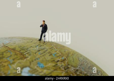 Miniatur-Geschäftsmann, Manager, auf einem Globus stehend Stockfoto
