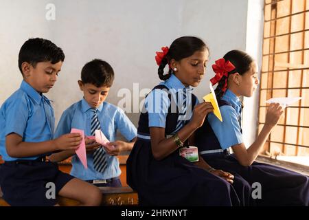 Kinder in der Schule spielen, indem sie Papierrakete aus dem Fenster aus dem Klassenzimmer werfen - Konzept des spielerischen Lebensstils der Kindheit, des Mangels an Lehrern und des Habens Stockfoto