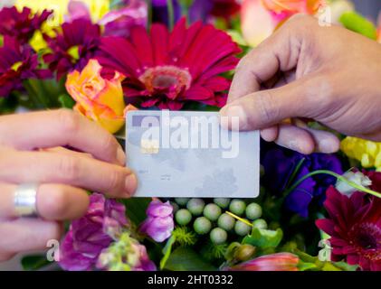 Wer sagt, Schönheit kann nicht gekauft werden. Kurzer Schuss einer Frau, die Blumen mit ihrer Kreditkarte von einem Floristen kauft. Stockfoto