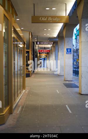 Stuttgart, 06. Januar 2022: Allee mit Geschäften und Architektursäulen. Gebäudefassade mit goldenen Akzenten. Schilder mit verschiedenen Marken. Stockfoto