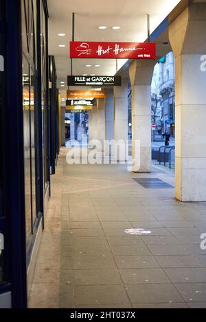 Stuttgart, 06. Januar 2022: Allee mit Geschäften und Architektursäulen. Gebäudefassade mit goldenen Akzenten. Schilder mit verschiedenen Marken. Stockfoto