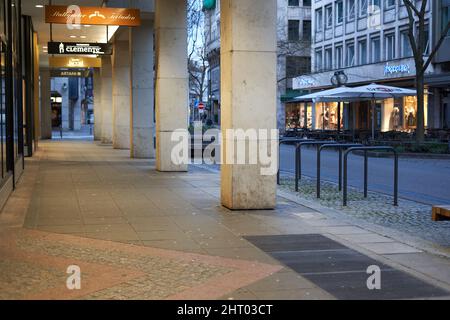 Stuttgart, 06. Januar 2022: Allee mit Geschäften und Architektursäulen. Gebäudefassade mit goldenen Akzenten. Schilder mit verschiedenen Marken. Stockfoto