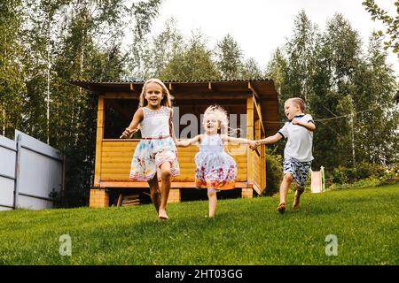 Glückliche Kinder laufen im Garten auf Gras. Sommerzeit. Stockfoto