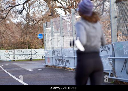 Stuttgart, 06. Januar 2022: Weg. Junge Frau beim Joggen im Winter. Weibliche Person von hinten, die in Winterkleidung Sport macht. Schärfentiefe. Stockfoto