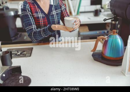 Nahaufnahme der weiblichen Hände, die eine Tasse Cappuccino halten Stockfoto