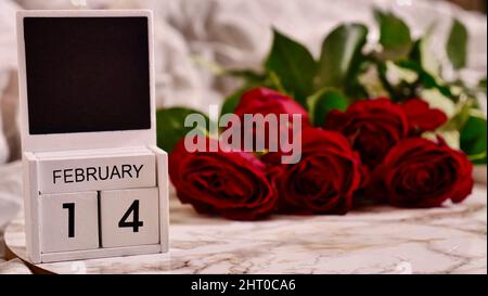 Festliches Flatlay, Komposition zum Valentinstag am 14. Februar. Kaffee in einer roten Tasse und rote Rosenblüten zu Hause im Bett Stockfoto