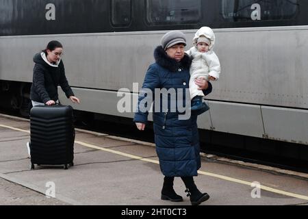 Eine Großmutter trägt ein Kind mit ihrer Tochter und folgt mit einem Koffer, während sie zum Wagen des Zuges gehen, um von Kramatorsk aus evakuiert zu werden. Der russische Präsident Wladimir Putin ordnete die militärische Intervention am 24. Februar an, Tage nach der Anerkennung von zwei von Separatisten gehaltenen Enklaven in der Ostukraine. Er behauptete, Moskau habe keinen Plan, das Nachbarland zu besetzen, sondern wolle die Ukraine „entmilitarisieren“ und „entnazifizieren“. Der ukrainische Präsident Wolodymyr Zelenskyy beschuldigte Russland, versucht zu haben, eine Marionettenregierung zu installieren, und sagte, die Ukrainer werden ihr Land gegen die russische Aggression verteidigen. Stockfoto