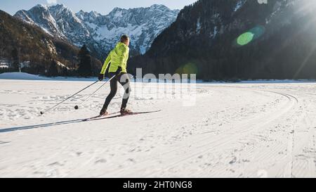 Kaukasische Freizeit mittleren Alters Mann Skilanglauf durch die Verwendung der Skating-Technik auf flachem schneebedeckten Gelände. Stockfoto