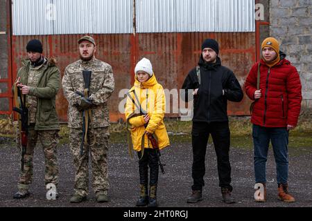 Non Exclusive: SIURTE, UKRAINE - 19. FEBRUAR 2022 - Ein Mädchen in einem weißen Hut und einem gelben Mantel hält ein Gewehr während einer militärischen Bohrübung für die Zivilbevölkerung Stockfoto