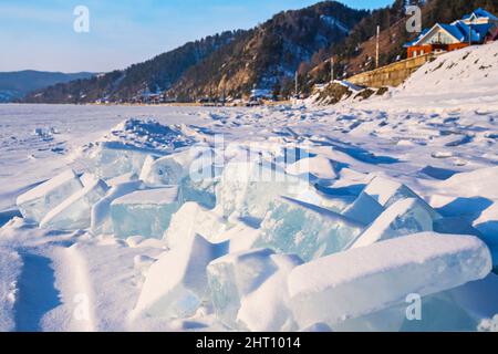 Die Höcker der durchsichtigen blauen schneebedeckten Eisschollen neben dem Dorf Listwjanka auf Juaikal. Eis- und Winterferien. Stockfoto