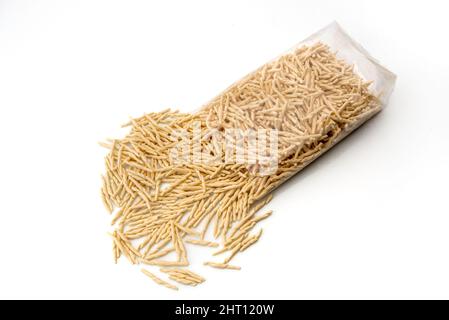 Trofie Pasta, typisch italienische Pasta aus Ligurien, roh getrocknet, die aus der transparenten Verpackung auf weißem Hintergrund kommen Stockfoto