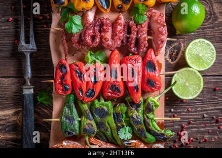 Gesund gegrillter Spieß mit Paprika, Tomaten und Zucchini. Shashlik mit gegrilltem Gemüse und Garnelen. Stockfoto