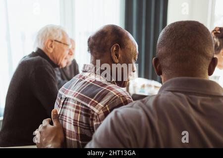 Männlicher Mitarbeiter im Gesundheitswesen, der sich im Pflegeheim um einen älteren Mann kümmert Stockfoto