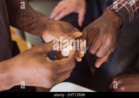 Zugeschnittenes Bild eines männlichen Pflegepersonals, der im Altersheim einen Nagellack auf einen älteren Mann anwendet Stockfoto