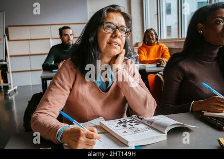Reife Schülerin sitzt mit Freunden im Klassenzimmer Stockfoto