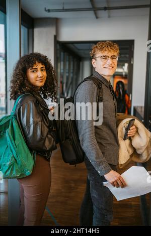 Lächelnde junge Studenten und Studenten blicken auf die Schultern der Community College Stockfoto