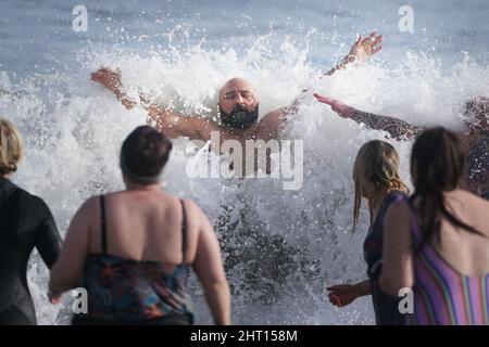 Schwimmer treffen sich mit Sol Kosepinar im Meer an der King Edward's Bay, Tynemouth, als er seine Herausforderung abschließt, 100 Tage lang täglich ein Bad im eiskalten Wasser der Nordostküste zu nehmen, um seine körperliche und geistige Gesundheit zu verbessern. Sol, der ursprünglich aus der Türkei stammt, stellte sich vor die Herausforderung, seine eigene psychische Gesundheit und den Stress, den er fühlt, wenn er in der Türkei abseits seiner Familie lebt, zu verbessern. Er hofft, andere dazu zu inspirieren, Meeresschwimmen zu versuchen, um ihrer eigenen psychischen Gesundheit zu helfen. Bilddatum: Samstag, 26. Februar 2022. Stockfoto