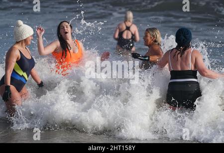 Schwimmer treffen sich mit Sol Kosepinar (nicht gesehen) im Meer an der King Edward's Bay, Tynemouth, als er seine Herausforderung abschließt, 100 Tage lang im eisigen Wasser der Nordostküste zu baden, um seine körperliche und geistige Gesundheit zu verbessern. Sol, der ursprünglich aus der Türkei stammt, stellte sich vor die Herausforderung, seine eigene psychische Gesundheit und den Stress, den er fühlt, wenn er in der Türkei abseits seiner Familie lebt, zu verbessern. Er hofft, andere dazu zu inspirieren, Meeresschwimmen zu versuchen, um ihrer eigenen psychischen Gesundheit zu helfen. Bilddatum: Samstag, 26. Februar 2022. Stockfoto