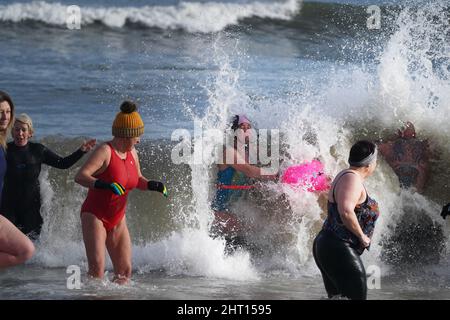 Schwimmer treffen sich mit Sol Kosepinar (nicht gesehen) im Meer an der King Edward's Bay, Tynemouth, als er seine Herausforderung abschließt, 100 Tage lang im eisigen Wasser der Nordostküste zu baden, um seine körperliche und geistige Gesundheit zu verbessern. Sol, der ursprünglich aus der Türkei stammt, stellte sich vor die Herausforderung, seine eigene psychische Gesundheit und den Stress, den er fühlt, wenn er in der Türkei abseits seiner Familie lebt, zu verbessern. Er hofft, andere dazu zu inspirieren, Meeresschwimmen zu versuchen, um ihrer eigenen psychischen Gesundheit zu helfen. Bilddatum: Samstag, 26. Februar 2022. Stockfoto