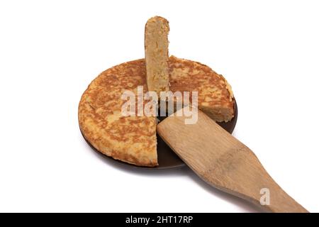 Kartoffelomelett, bekannt als „Spanisches Omelett“. Mit einem Holzlöffel. Sehr verbraucht in Spanien. Isoliert auf weißem Hintergrund. Spanisches Speisekonzept. Stockfoto