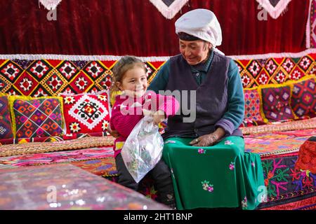 Kashgar, China. 24.. Februar 2022. (220226) -- KASHGAR, 26. Februar 2022 (Xinhua) -- Ein Kind plaudert mit ihrer Familie zu Hause im Dorf Rasekam des taxkorgan Tajik Autonomen Kreises, im Nordwesten der Autonomen Region Xinjiang Uygur in China, 24. Februar 2022. Rasekam ist ein kleiner Weiler, der sich auf dem Pamir Plateau befindet, mit einer durchschnittlichen Höhe von 3.000 Metern über dem Meeresspiegel. Früher bestand Rasekam aus 12 Gruppen von Hirten, die verstreut in der Bergregion residierten, war das Dorf arm an Transport und Lebensunterhalt. Seit 2017 hat die lokale Regierung damit begonnen, Einheimische aus der unwirtlichen Gegend zu verlagern Stockfoto