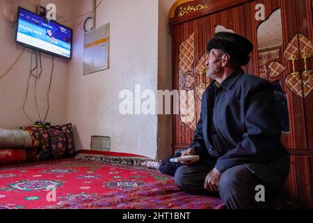 Kashgar, China. 24.. Februar 2022. (220226) -- KASHGAR, 26. Februar 2022 (Xinhua) -- Ein Dorfbewohner schaut zu Hause im Dorf Rasekam im taxkorgan tadschikischen Autonomen Kreis, nordwestlich der Autonomen Region Xinjiang Uygur in China, am 25. Februar 2022 Fernsehen. Rasekam ist ein kleiner Weiler, der sich auf dem Pamir Plateau befindet, mit einer durchschnittlichen Höhe von 3.000 Metern über dem Meeresspiegel. Früher bestand Rasekam aus 12 Gruppen von Hirten, die verstreut in der Bergregion residierten, war das Dorf arm an Transport und Lebensunterhalt. Seit 2017 hat die lokale Regierung damit begonnen, Einheimische aus den unwirtlichen Gebieten in neue zu verlagern Stockfoto