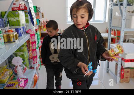 Kashgar, China. 24.. Februar 2022. (220226) -- KASHGAR, 26. Februar 2022 (Xinhua) -- Kinder kaufen Snacks in einem Geschäft im Dorf Rasekam im Taxkorgan Tajik Autonomen Kreis, nordwestlich der Autonomen Region Xinjiang Uygur in China, 24. Februar 2022. Rasekam ist ein kleiner Weiler, der sich auf dem Pamir Plateau befindet, mit einer durchschnittlichen Höhe von 3.000 Metern über dem Meeresspiegel. Früher bestand Rasekam aus 12 Gruppen von Hirten, die verstreut in der Bergregion residierten, war das Dorf arm an Transport und Lebensunterhalt. Seit 2017 hat die lokale Regierung damit begonnen, Einheimische aus den unwirtlichen Gebieten in neue zu verlagern Stockfoto