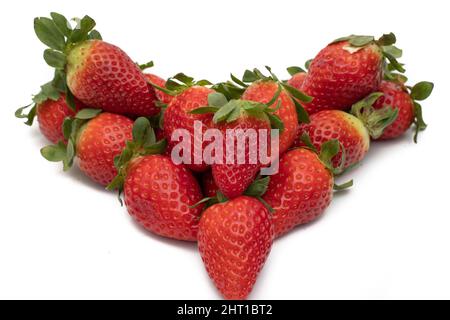 Ein Bund voller Erdbeeren mit ihren grünen Blättern, die in Form eines Herzens angelegt sind. Isoliert auf weißem Hintergrund. Stockfoto