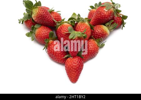 Ein Bund voller Erdbeeren mit ihren grünen Blättern, die in Form eines Herzens angelegt sind. Isoliert auf weißem Hintergrund. Stockfoto