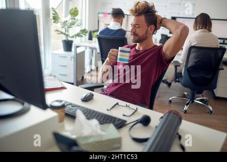 Überarbeiteter kaukasischer Mann, der versucht, sich im Büro zu konzentrieren Stockfoto