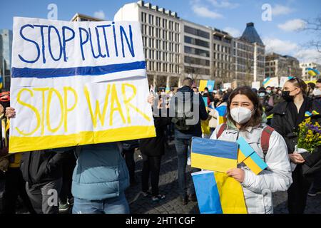 26. Februar 2022, Hessen, Frankfurt/Main: Auf der Veranstaltung „Solidarität mit der Ukraine – Frieden in Osteuropa“, die von Bündnis 90/die Grünen am Rathenauplatz organisiert wurde, halten Menschen Schilder mit „Stop Putin - Stop war“ und ukrainischen Fahnen. Foto: Hannes P. Albert/dpa Stockfoto