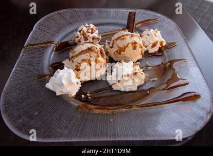 Ein sehr leckeres Dessert. Luis Felipe Mousse, Schokolade mit Creme und Karamell. Im Hintergrund eine unfokussierte Frau. Spanisches Speisekonzept. Stockfoto