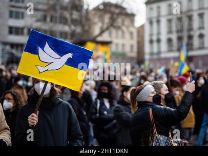 Stuttgart, Deutschland. 26.. Februar 2022. Während einer Demonstration gegen den russischen Militäreinsatz in der Ukraine hält eine Frau am Wilhelmsplatz ein Schild mit den Farben der ukrainischen Flagge und einer Friedenstaube in der Hand. Quelle: Christoph Schmidt/dpa/Alamy Live News Stockfoto