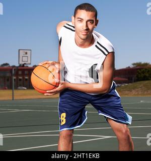 Ich habe Fähigkeiten erworben. Ein junger Basketballspieler bereitet sich darauf vor, einen Ball zu dribbeln. Stockfoto