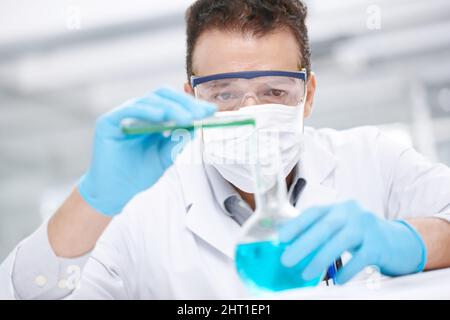 Gefährliches Experiment. Nahaufnahme eines Chemikers, der zwei Chemikalien zusammengießt. Stockfoto