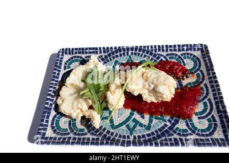 Gebratener Kabeljau mit Marmelade-Sauce, auf einem dekorativen rechteckigen Teller. Innovatives Lebensmittelkonzept. Stockfoto