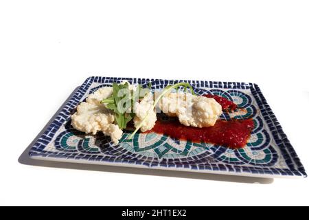 Gebratener Kabeljau mit Marmelade-Sauce, auf einem dekorativen rechteckigen Teller. Innovatives Lebensmittelkonzept. Stockfoto