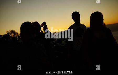 Beenden Sie den Tag mit einem wunderschönen Sonnenuntergang. Silhouette einer Gruppe von Freunden gegen einen gelben Sonnenuntergang. Stockfoto